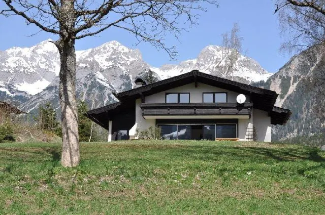 Das Landhaus Blaubeerhügel auf der Frühlingswiese, dahinter die verschneiten Gipfel des Dachsteins