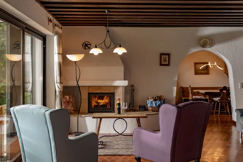 Sitzecke mit Ohrensessel vor dem offenen Kamin