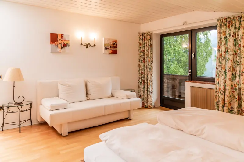 Schlafzimmer mit Doppelbett und weißem Schlafsofa